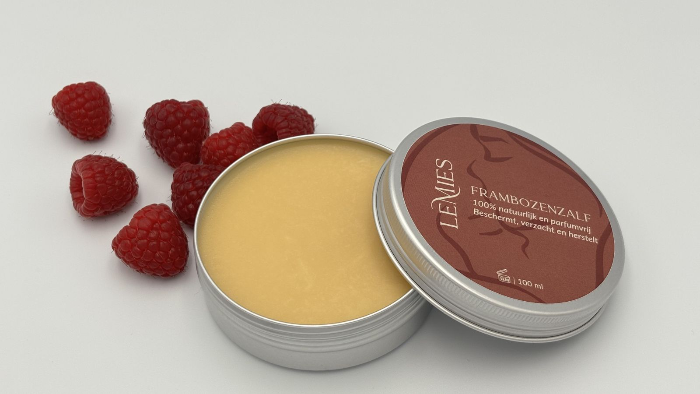 Open potje frambozenzalf met losse frambozen ernaast